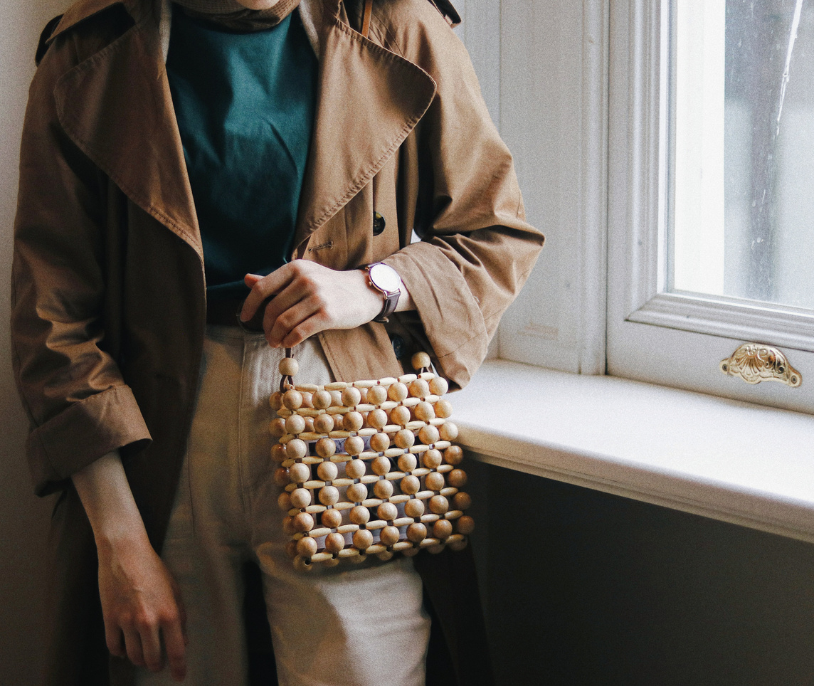 Crop stylish woman with handbag against window