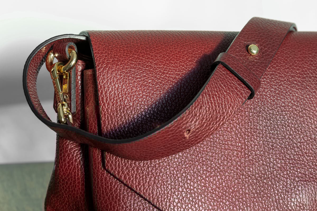 a fragment of a burgundy leather women's bag with shoulder strap